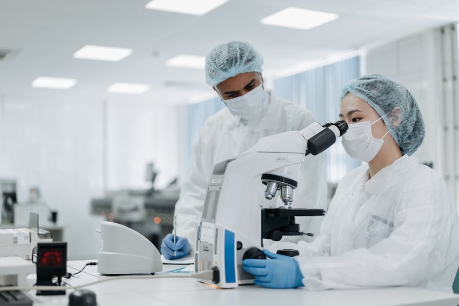 Scientists in protective suits examining samples under a microscope, focusing on microbiological research.